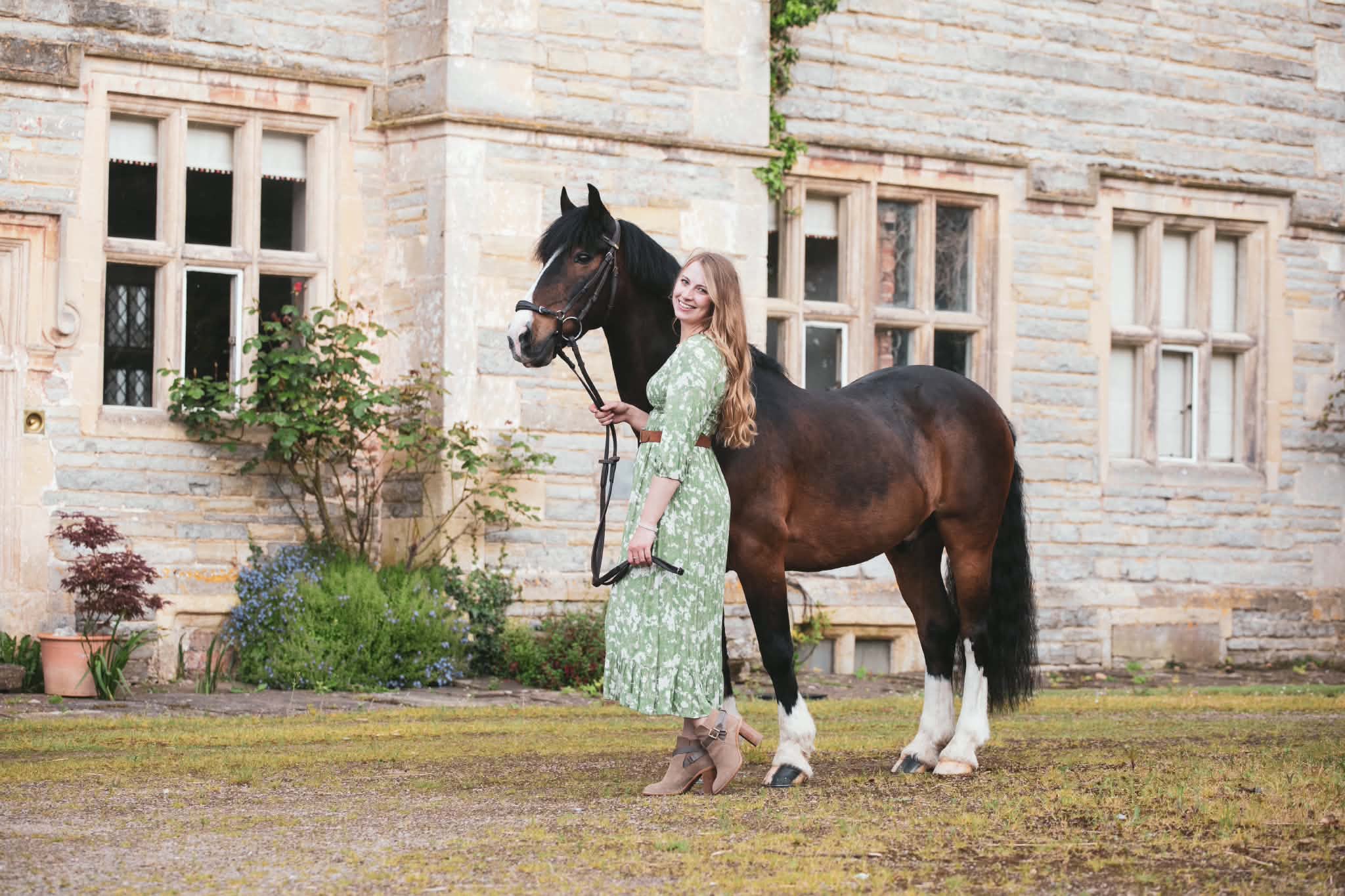 Sophie Bennett with a horse outside a stone manor house